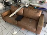 a brown leather couch that has a knife stuck in it