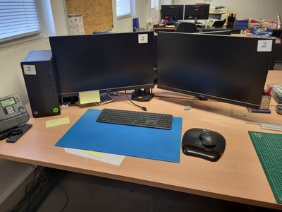 un bureau sur lequel sont posés deux écrans d'ordinateur et un clavier