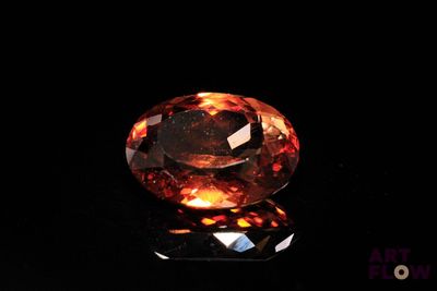 a close up of an orange diamond on a black surface