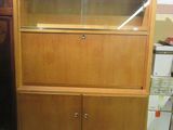 a wooden cabinet with a glass door on top of it