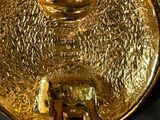a close up of a gold plate with a face on it