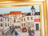 une photo d'un tableau représentant une scène de rue, dans un cadre doré