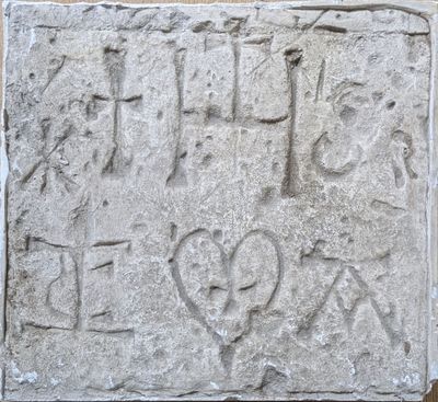 un bloc de pierre portant une inscription, fixé à un mur