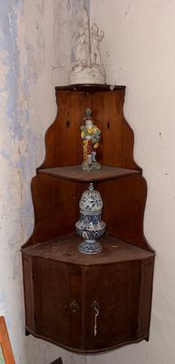 une étagère d'angle placée dans un coin de la pièce, sur laquelle se trouve un vase