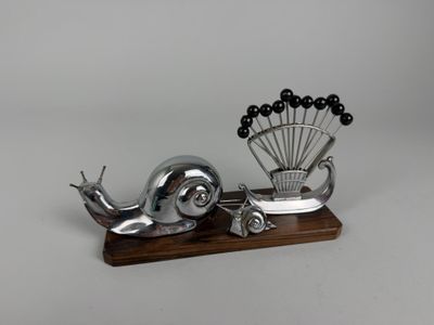 a metal sculpture of a snail and a peacock on a wooden stand
