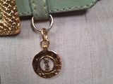 a purse with a gold charm hanging from it ' s side