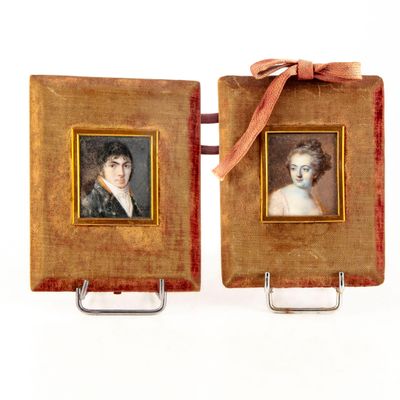 pair of framed portraits of a woman and a man with a red ribbon