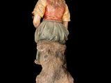 statue of a woman sitting on a rock with her back to the camera
