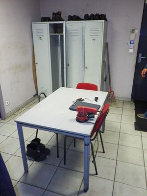 a white table with red chairs in a room with lockers