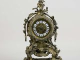 a clock that is sitting on a stand on a white surface
