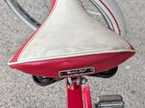 a red bike with a white seat and a black handlebar