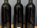 four bottles of wine are lined up on a wooden table