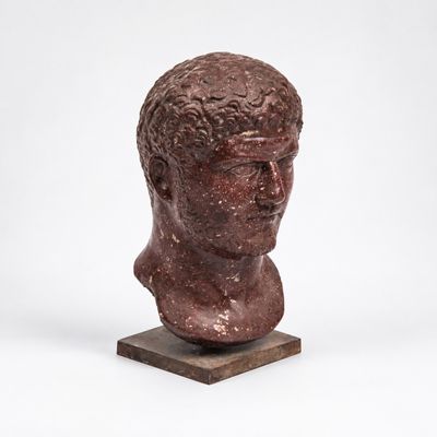 une statue représentant la tête d'un homme posée sur un socle en bois