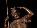 bronze statue of a man holding a spear and a bird