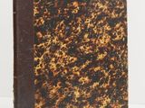 an old book with a brown cover sitting on top of a table