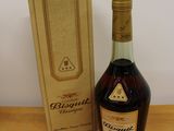 the bottle of brandy is next to the box on the table