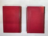 two red books sitting on top of each other on a white surface
