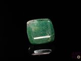 an emerald stone on a black surface with a black background