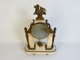 a clock that is sitting on a stand with a mirror