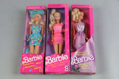 three barbie dolls are in a pink box on a table