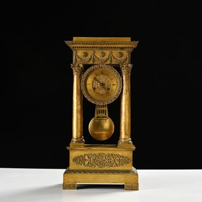 une horloge dorée posée sur une table, sur fond noir