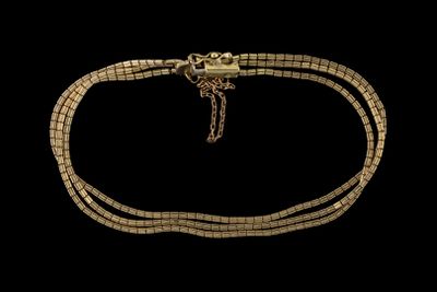 gros plan d'un collier en or sur fond noir