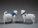 two figurines of a dog with a blue ribbon around its neck