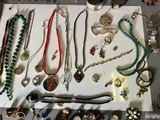 many different necklaces and bracelets displayed on a table