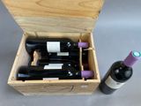 two bottles of wine in a wooden box next to a bottle of wine
