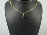 a black and gold necklace with a blue stone on a mannequin