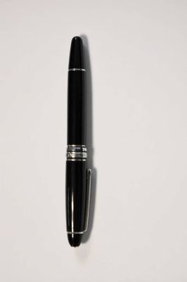 un gros plan d'un stylo posé sur une surface blanche, avec une ombre