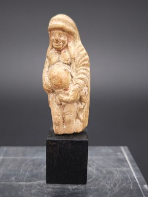 une vieille figurine sculptée représentant un homme tenant un enfant dans ses bras
