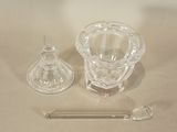 a glass candle holder and a glass spoon on a table