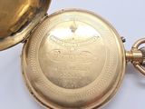 a gold pocket watch sitting on a white surface