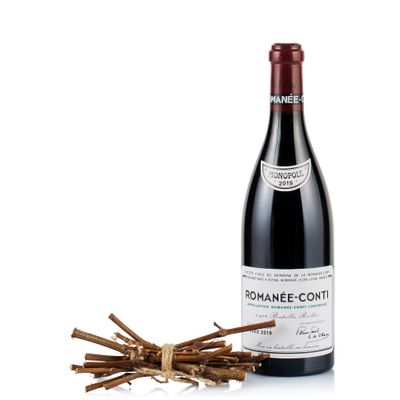 a bottle of red wine next to a bunch of sticks
