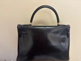 a black purse sitting on top of a table next to a wall