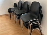 Plusieurs chaises noires sont alignées contre un mur dans une salle d'attente