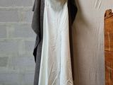 a white dress hanging on a clothes rack next to a dresser