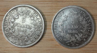 two silver coins sitting side by side on a wooden surface