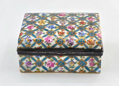 une petite boîte décorée de fleurs, posée sur une surface blanche