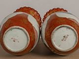 pair of red and white vases sitting on top of a wooden table