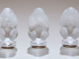 trois figurines en verre posées sur une surface blanche