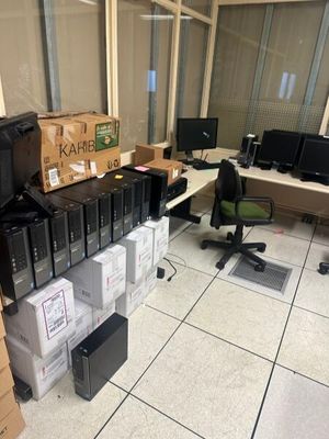 une pièce où il y a beaucoup de cartons et d'ordinateurs par terre
