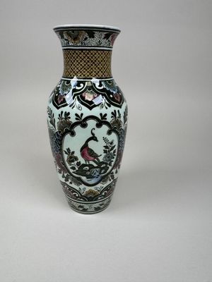 a vase with a bird on it sitting on a table