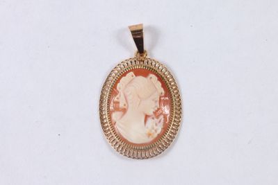 a close up of a gold pendant with a woman ' s profile