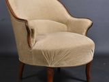 a beige upholstered chair with wooden legs and a curved back