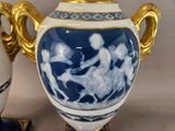 a blue and white vase sitting next to a white and gold vase