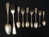 six spoons and a fork are lined up on a black surface