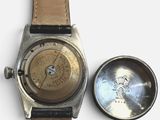 a watch that is sitting next to a metal cup
