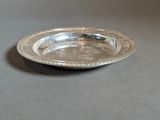 a small silver plate on a table with a black background